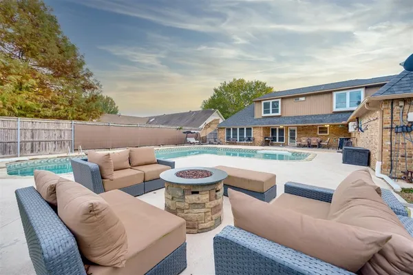 a view of a patio with couches and a fire pit and wooden fence