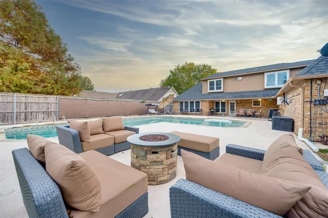a view of a patio with couches and a fire pit and wooden fence