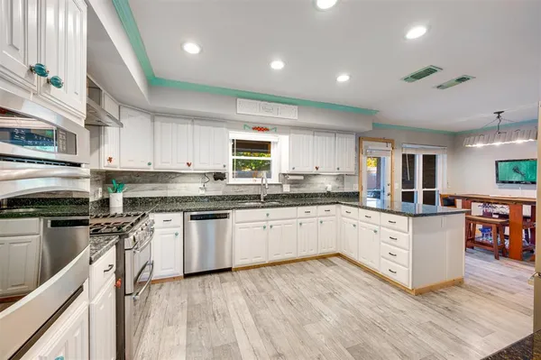 a kitchen with stainless steel appliances granite countertop a stove top oven a sink dishwasher and a microwave oven with large wooden cabinets