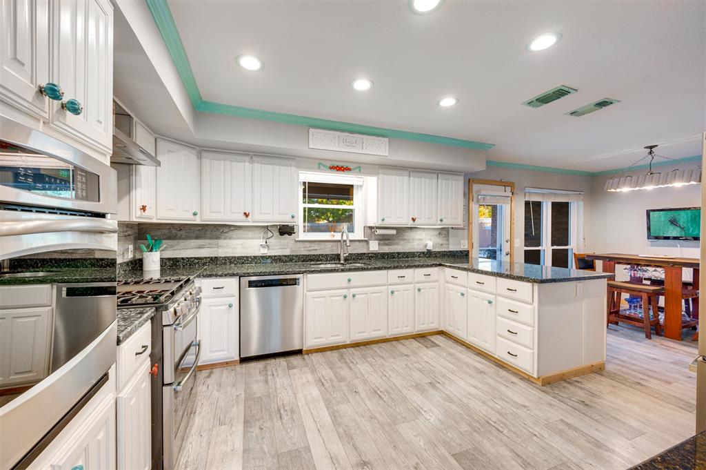 4115 Alpine Street Paris, TX 75462 - Photo 8 of 40 a kitchen with stainless steel appliances granite countertop a stove top oven a sink dishwasher and a microwave oven with large wooden cabinets