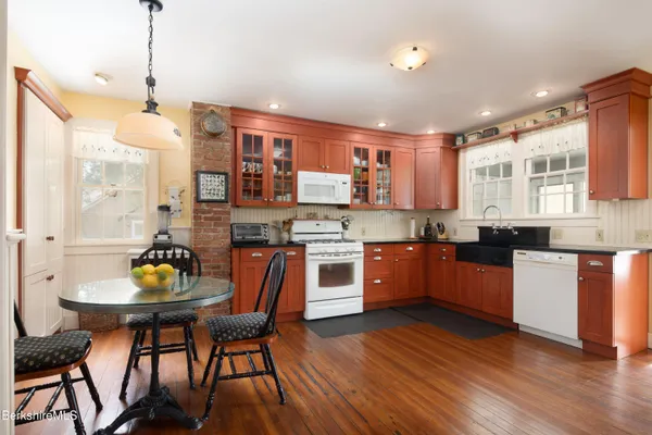 a kitchen with stainless steel appliances granite countertop a stove a sink dishwasher a dining table and chairs with wooden floor