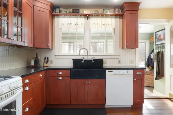 a kitchen with granite countertop a sink a counter space appliances and cabinets