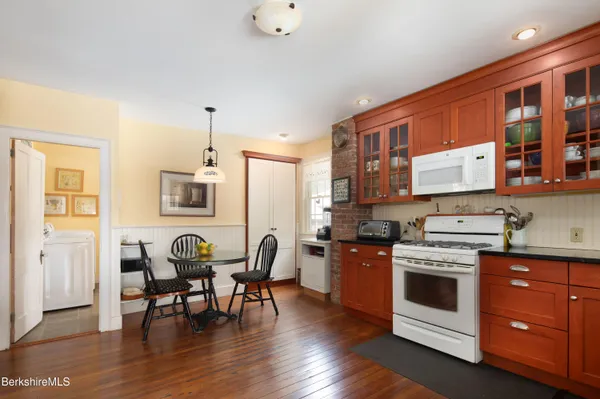a open kitchen with stainless steel appliances granite countertop a stove top oven a dining table and chairs with wooden floor