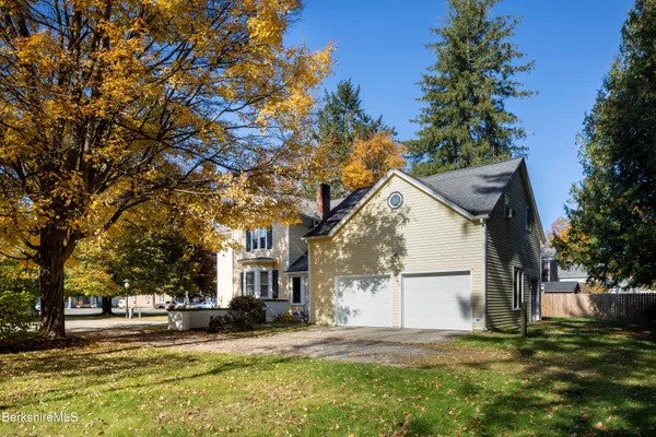 a view of a house with a yard and large tree