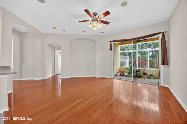 a view of an empty room with a window and wooden floor