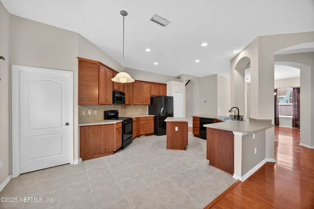 a view of kitchen with stainless steel appliances granite countertop refrigerator sink and wooden cabinets