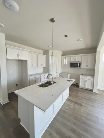 a large kitchen with kitchen island a stove a sink a refrigerator and white cabinets with wooden floor