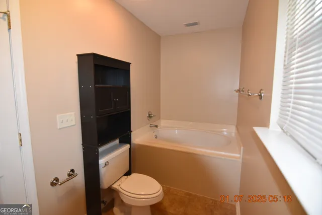 a bathroom with a granite countertop bathtub shower sink vanity and toilet