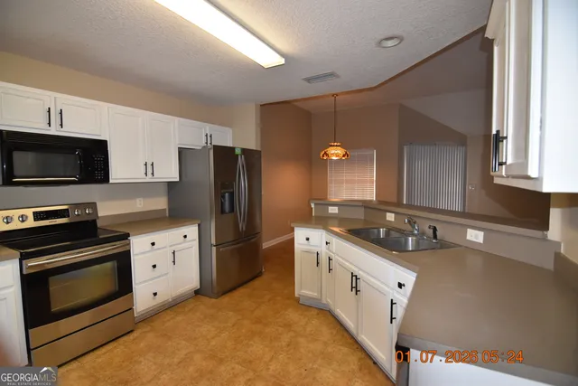 a kitchen with stainless steel appliances granite countertop a stove a sink and a refrigerator