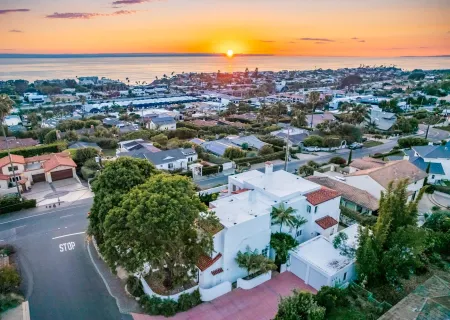 an aerial view of a city with lots of residential buildings ocean and mountain view in back