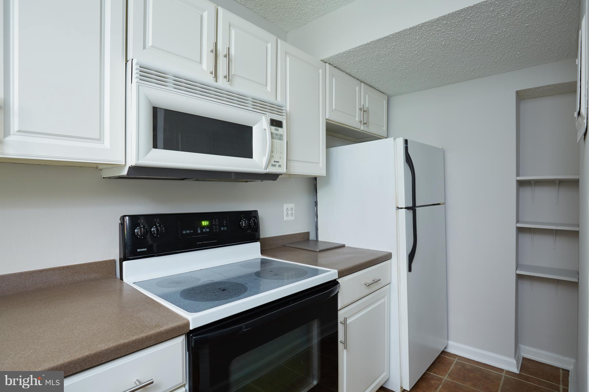 4004 Beecher Street Northwest, Unit 102 Washington, DC 20007 - Photo 7 of 24 a kitchen with a refrigerator and a stove top oven