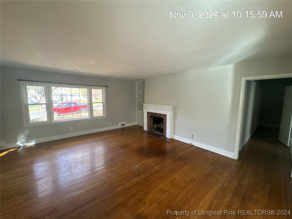 1429 Pine Valley Loop Fayetteville, NC 28305 - Photo 8 of 27 an empty room with wooden floor fireplace and windows