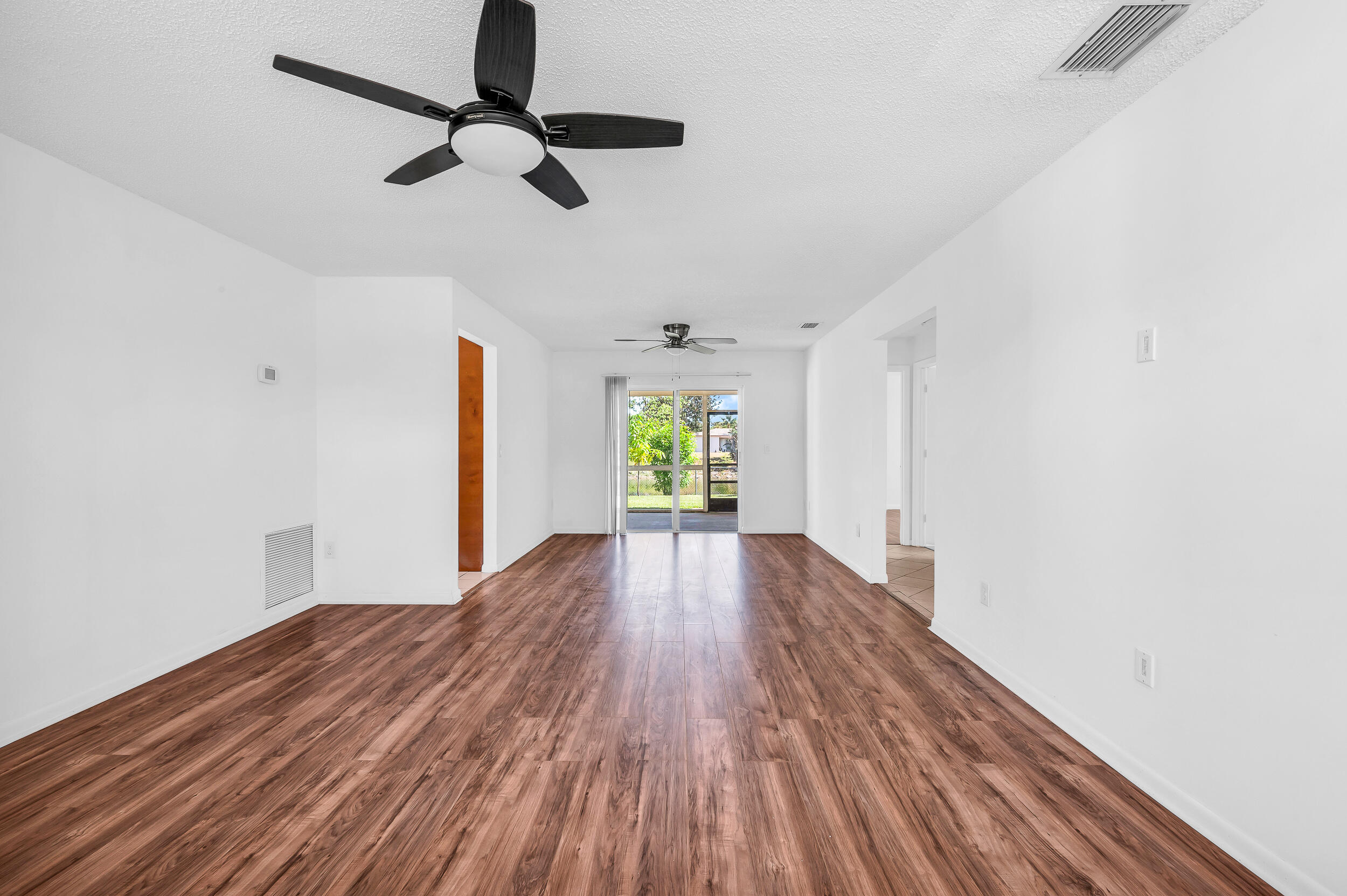 10905 Eureka Street Boca Raton, FL 33428 - Photo 2 of 16 a view of empty room with wooden floor and fan