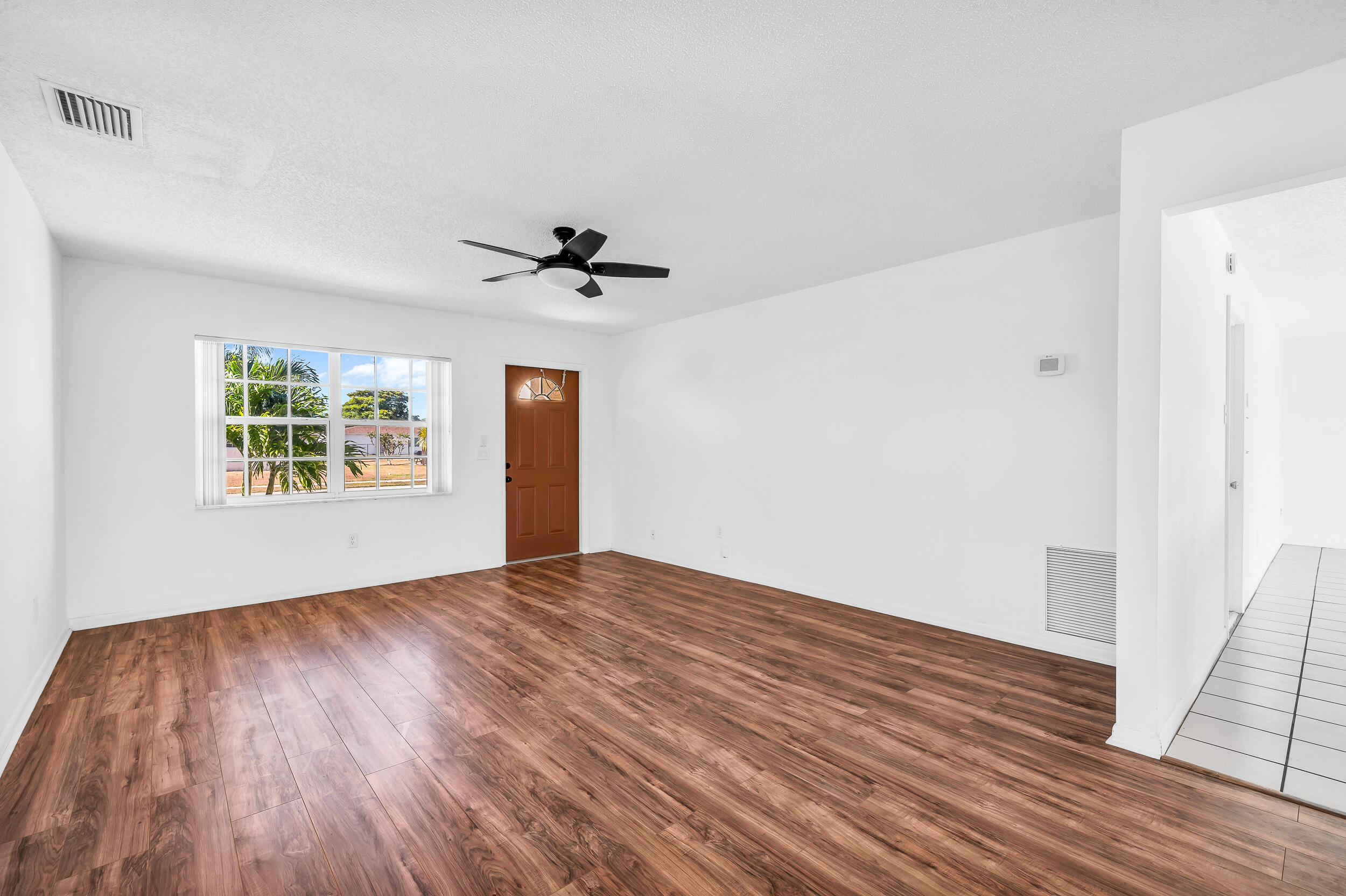10905 Eureka Street Boca Raton, FL 33428 - Photo 3 of 16 a view of an empty room with windows and wooden floor