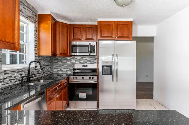 a kitchen with stainless steel appliances granite countertop a stove a refrigerator and a sink