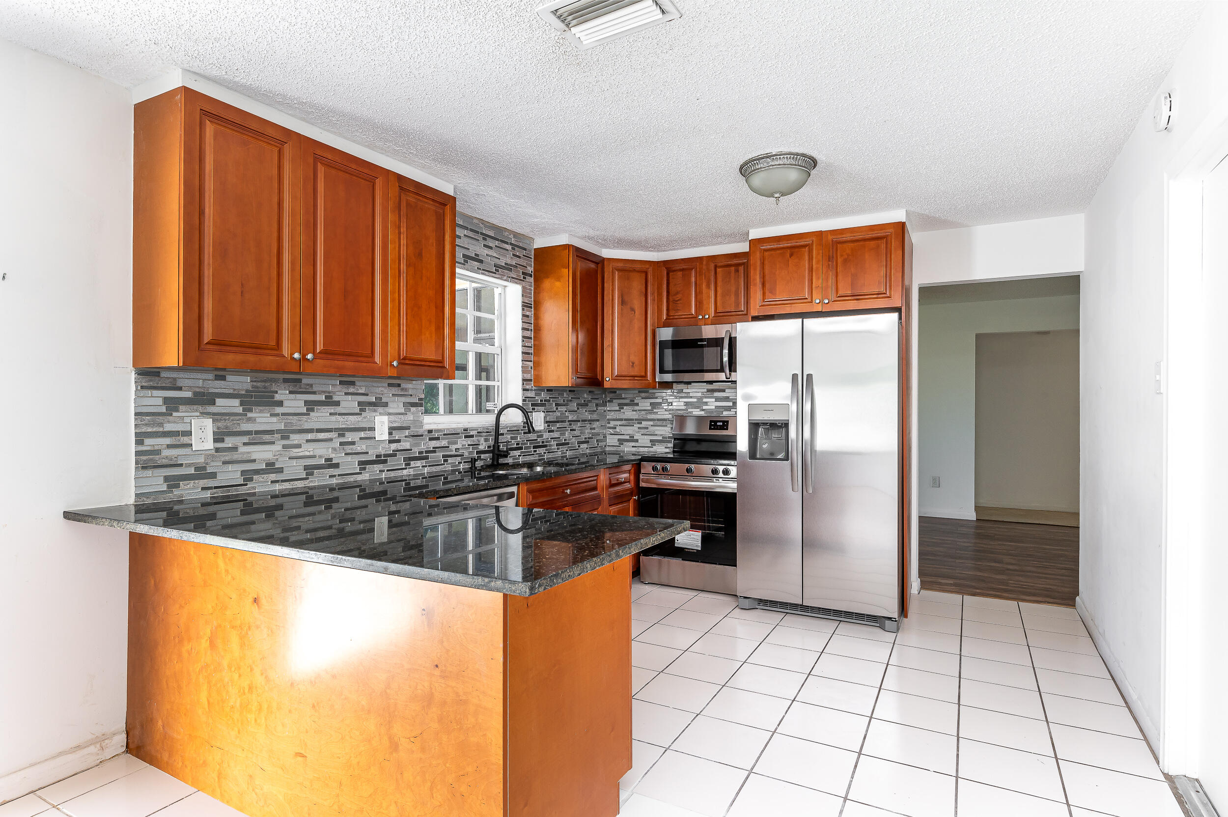 10905 Eureka Street Boca Raton, FL 33428 - Photo 9 of 16 a kitchen with granite countertop a refrigerator and a sink