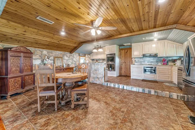 a dining room with stainless steel appliances kitchen island granite countertop a table chairs and a refrigerator