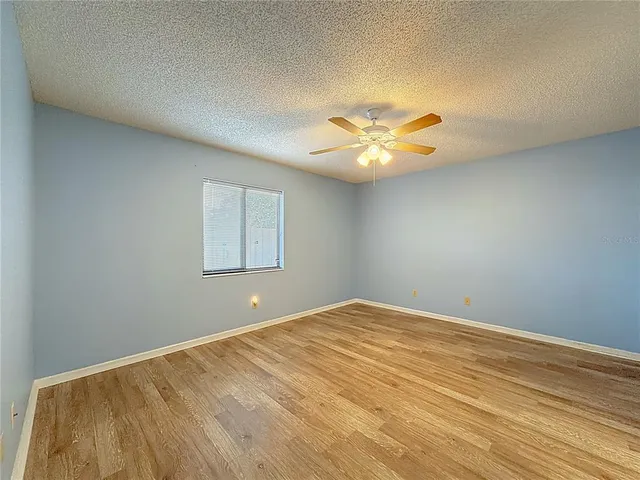 a view of a big room with wooden floor and a chandelier fan