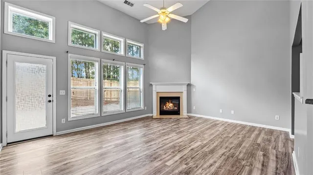 a view of empty room with wooden floor and fan