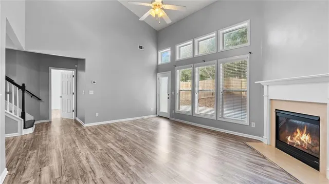 a view of an empty room with wooden floor fireplace and a window