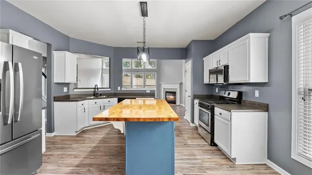 a kitchen with stainless steel appliances kitchen island granite countertop a refrigerator a sink dishwasher a stove with wooden cabinets and floor