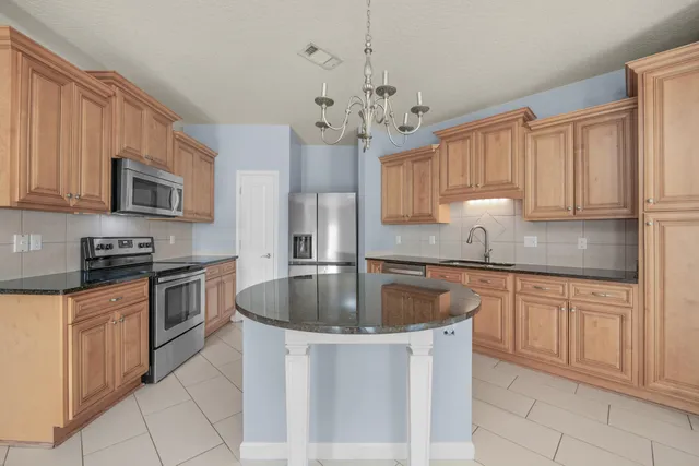 a kitchen with stainless steel appliances granite countertop a stove a sink and a refrigerator