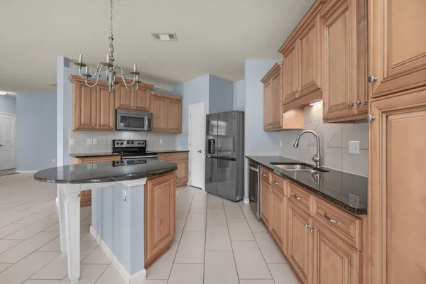a large white kitchen with kitchen island a sink stainless steel appliances and cabinets