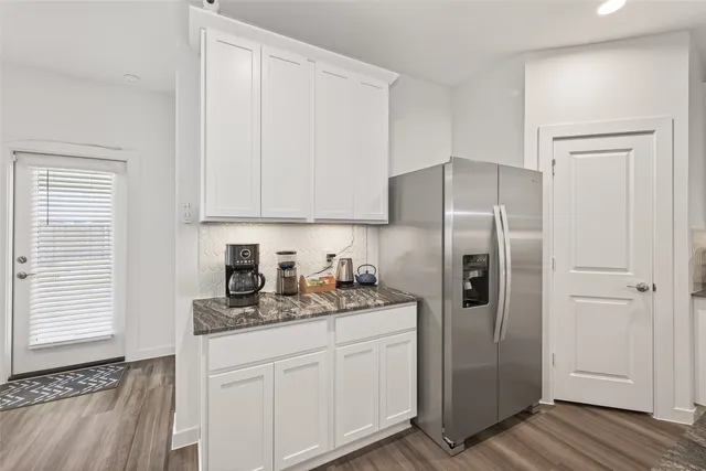 a kitchen with stainless steel appliances granite countertop a refrigerator and white cabinets