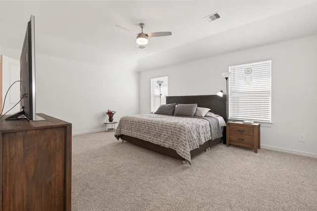 a spacious bedroom with a bed and a flat screen tv