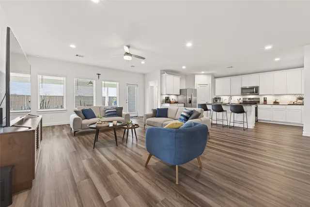 a living room filled with furniture wooden floor and a kitchen view