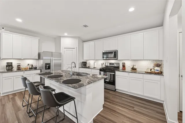 a kitchen with a stove a sink a refrigerator and cabinets