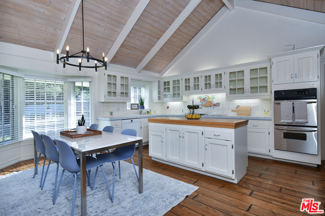 4525 Comber Avenue Encino, CA 91316 - Photo 10 of 30 a kitchen with a stove a sink dishwasher a dining table and chairs with wooden floor