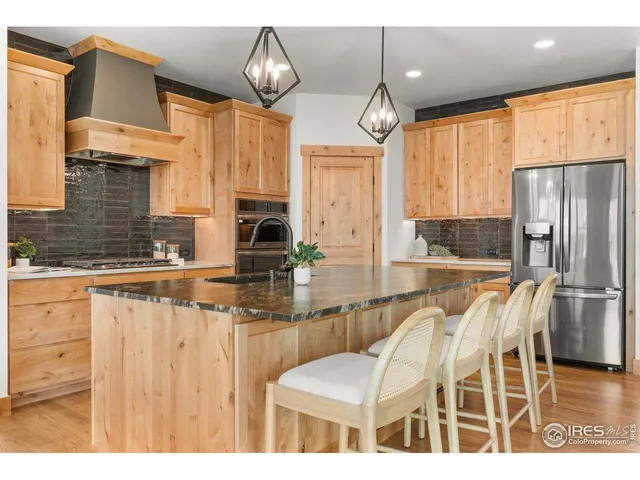 a kitchen with stainless steel appliances kitchen island granite countertop a table chairs and a refrigerator