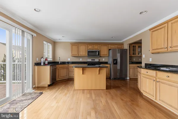 a kitchen with granite countertop a refrigerator oven a sink dishwasher and white cabinets with wooden floor