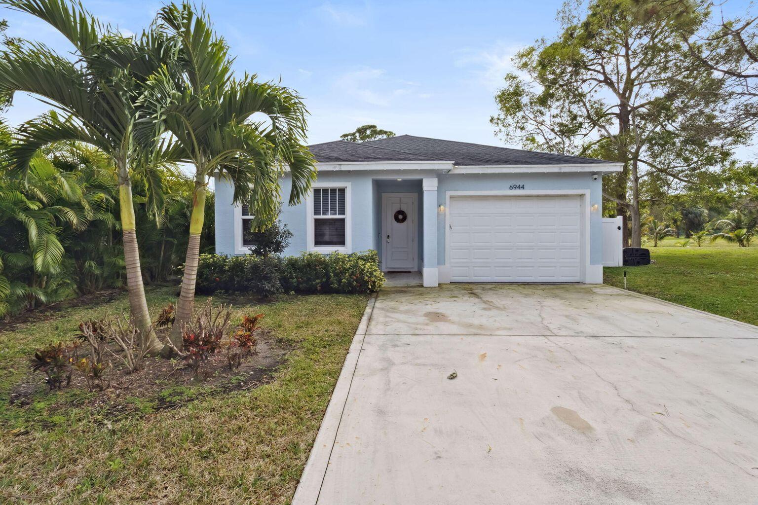 6944 2nd Street Jupiter, FL 33458 - Photo 23 of 26 a front view of a house with a yard and garage