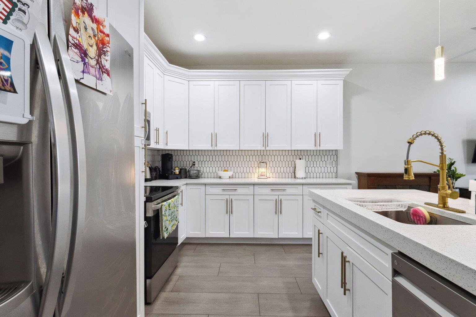 6944 2nd Street Jupiter, FL 33458 - Photo 3 of 26 a kitchen with stainless steel appliances granite countertop a refrigerator sink and white cabinets