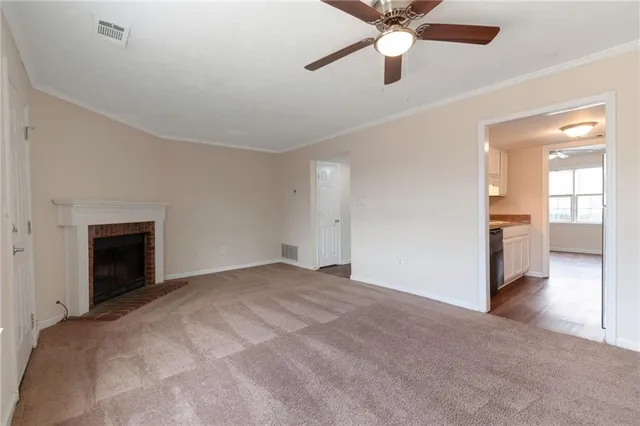a view of an empty room with a fireplace and a ceiling fan
