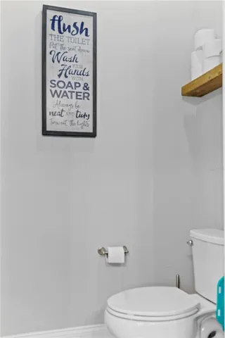 a white toilet sitting next to a white wall and a shower