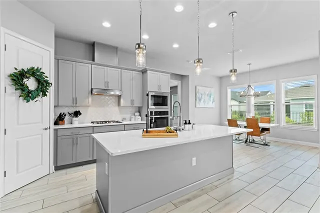 a kitchen with a refrigerator a sink dishwasher a stove and white cabinets with wooden floor