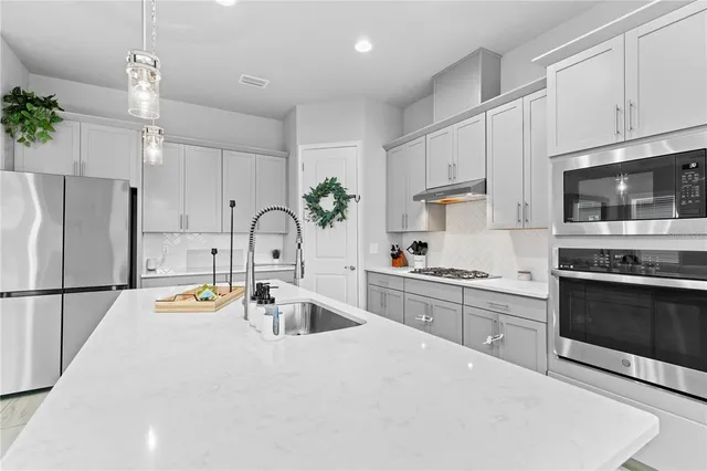 a kitchen with granite countertop a sink stainless steel appliances and white cabinets