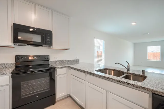 a kitchen with granite countertop white cabinets and stainless steel appliances