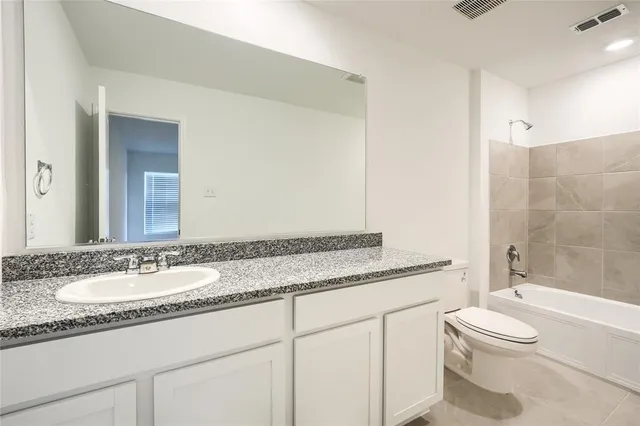 a bathroom with a granite countertop sink mirror vanity and toilet