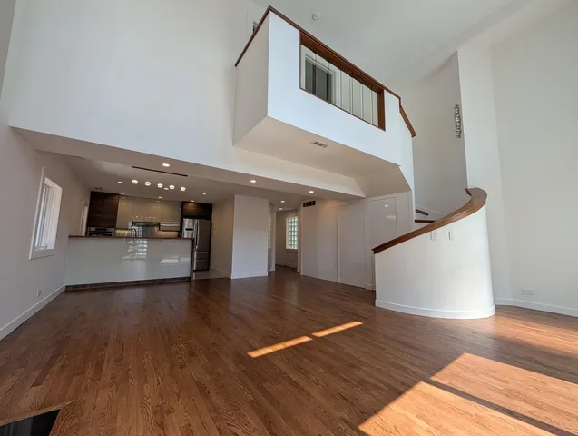 a view of an empty room with wooden floor and a ceiling fan
