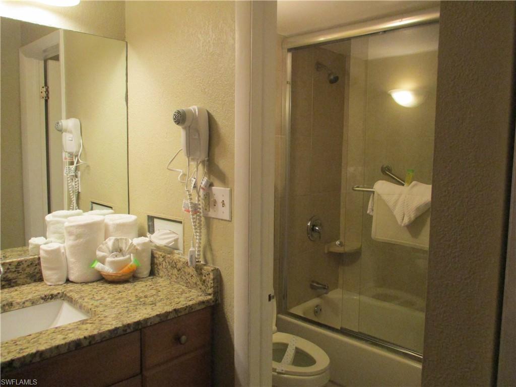 2555 9th Street North, Unit 131 Naples, FL 34103 - Photo 8 of 17 a bathroom with a granite countertop sink a toilet and shower