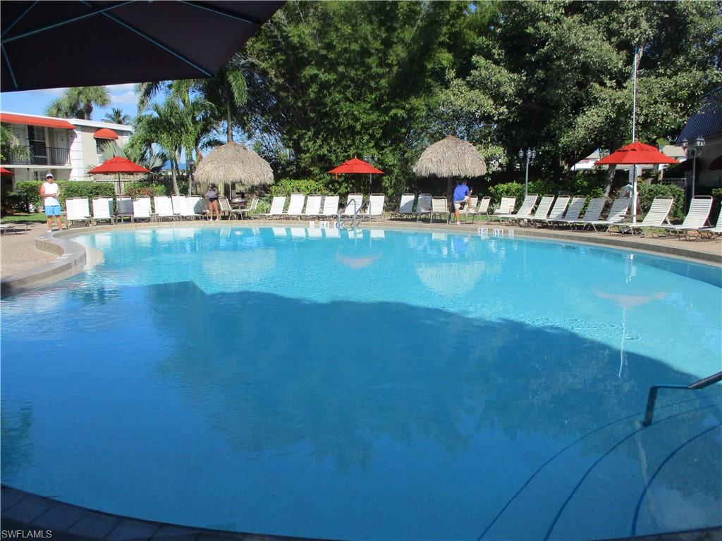 2555 9th Street North, Unit 131 Naples, FL 34103 - Photo 10 of 17 a view of swimming pool with a table and chairs under an umbrella