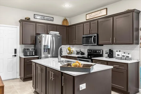 a kitchen with stainless steel appliances a refrigerator a sink a stove a microwave and wooden cabinets