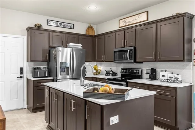 a kitchen with stainless steel appliances a refrigerator a sink a stove a microwave and wooden cabinets