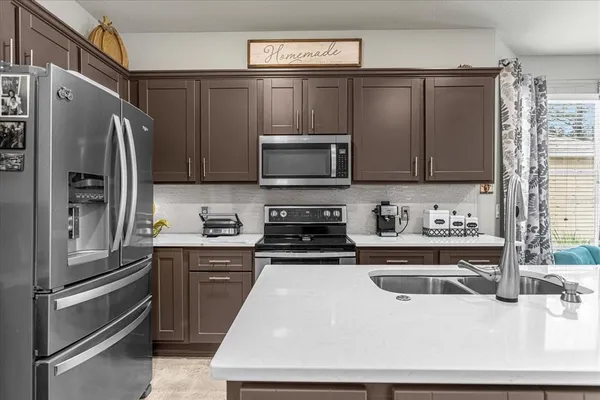 a kitchen with stainless steel appliances a stove a sink a refrigerator and cabinets