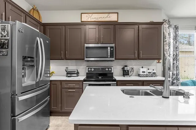 a kitchen with stainless steel appliances a stove a sink a refrigerator and cabinets