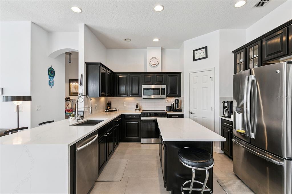 1652 Cherry Ridge Drive Lake Mary, FL 32746 - Photo 17 of 62 a kitchen with stainless steel appliances a sink a stove a refrigerator cabinets and chairs